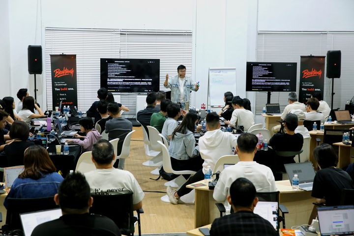Jia Wei 在 Breakthrough Live 前面讲, 两边屏幕, 满场笔电
